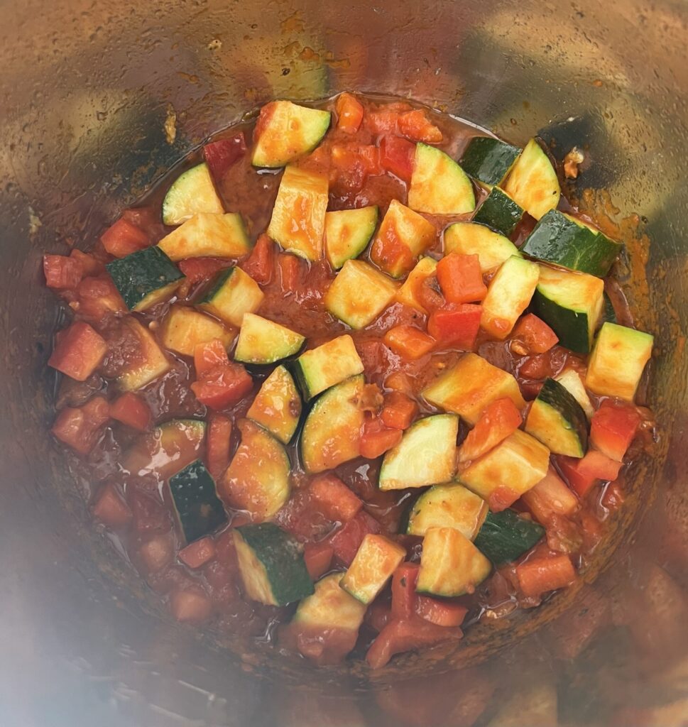 Scrape the bottom of the pot of any chicken remains and stir in the marinara sauce (keep the remains in for extra flavor).  Then, add the chopped zucchini and bell pepper. 