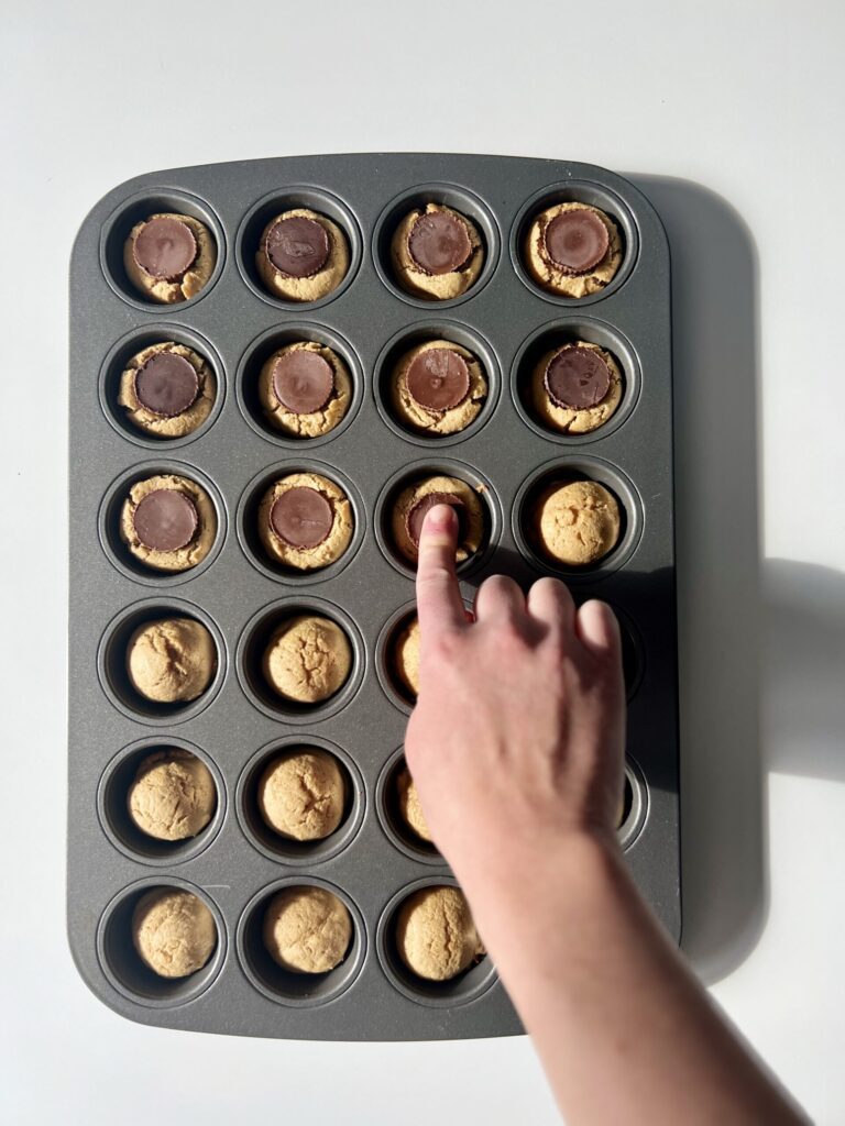 Once baked, press the peanut butter cup into each dough ball