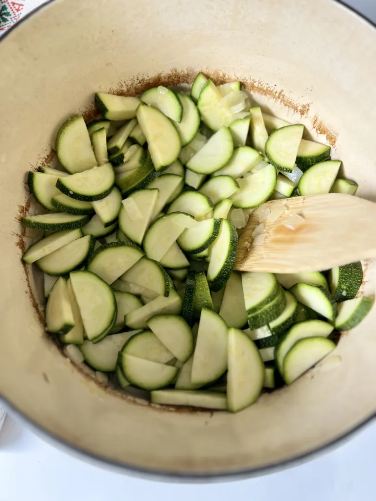 Next, add the sliced zucchini to the pot and saute for 5 minutes. Then add the turmeric, ginger, and cumin, and stir to combine.