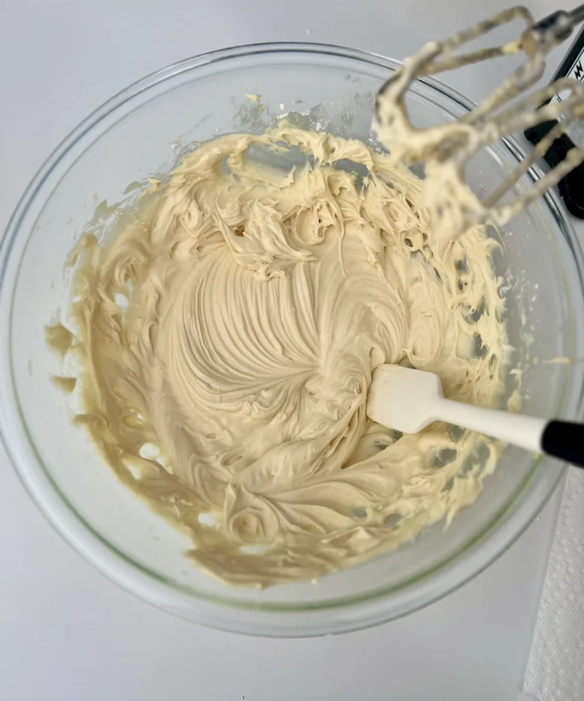 increase the mixer speed to medium and continue to blend until the frosting becomes smooth and well combined. Be sure to scrape down the sides of the bowl with a spatula to ensure even mixing.