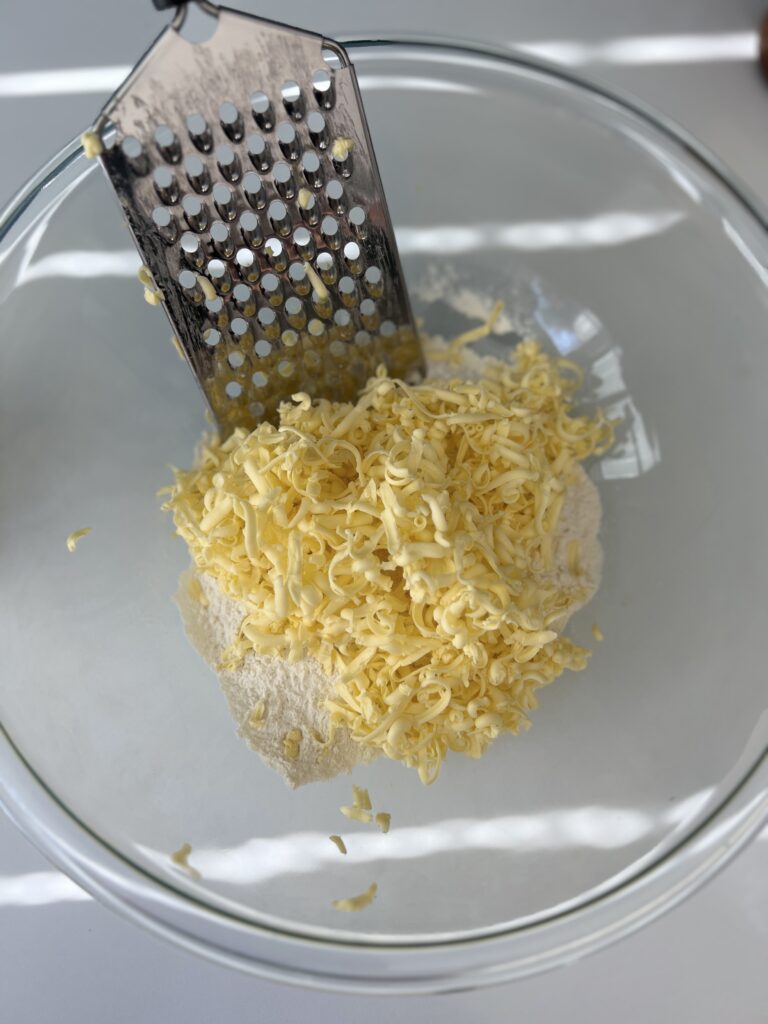 Next, add the cold butter by grating it into the mixture (alternatively you can cut the butter into small cubes). 