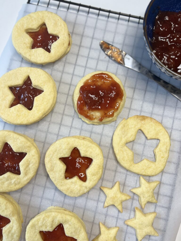 Take one bottom piece of the cookie, spread 2 teaspoons of jam on top, and place the top piece of the cookie over it. Repeat until all cookies have been assembled. 