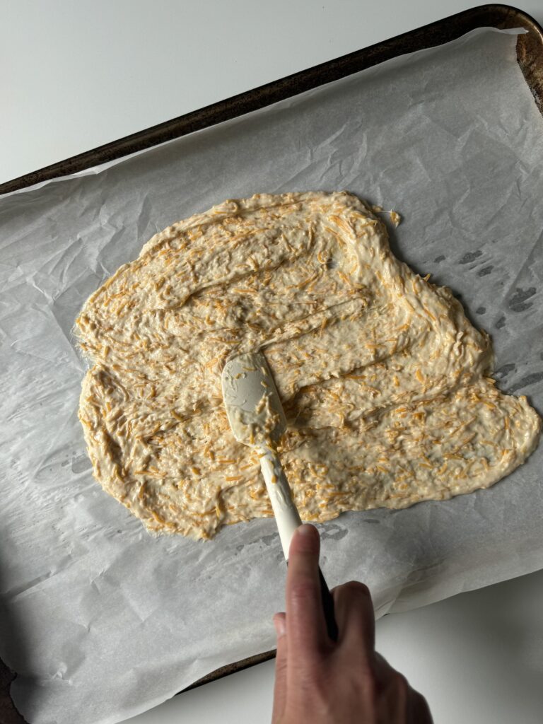 spreading sourdough cheese cracker dough